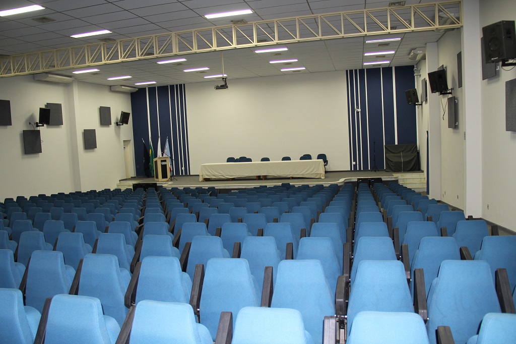 Foto do interior do Salão de Convenções mostrando suas cadeiras e palco.